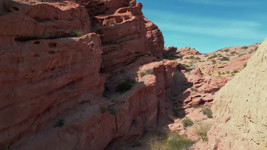 Drone view of the red rocks "Los Colorados" near Cafayate in the Salta province in Argentina. Drone shot flying up from behind the rocks to reveal the valleys and landscape beyond