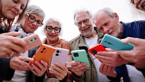 Group of seniors Caucasian surprised people using colourful smart phone together standing in circle outdoor. Joyful mature gray hair friends meeting having fun enjoying looking smiling cell mobile  - Powered by Shutterstock - Get 15% off with code: PIKWIZARD15
