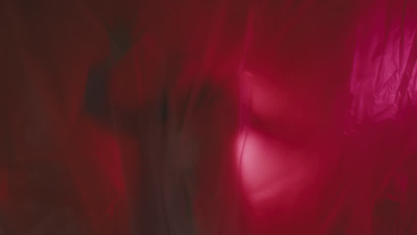 Slow shutter effect. A woman in a pink blazer is trying to get out of plastic wrap 