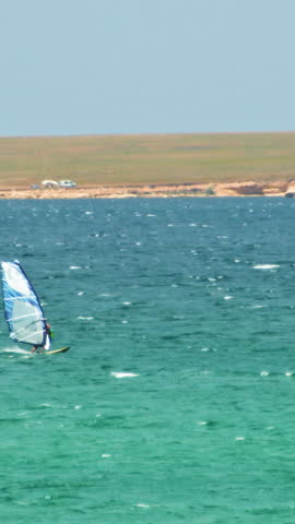 Man Windsurfing in the water during a sunny summer day. Shot. Beautiful view of the sea and windsurfer on a Sunny day