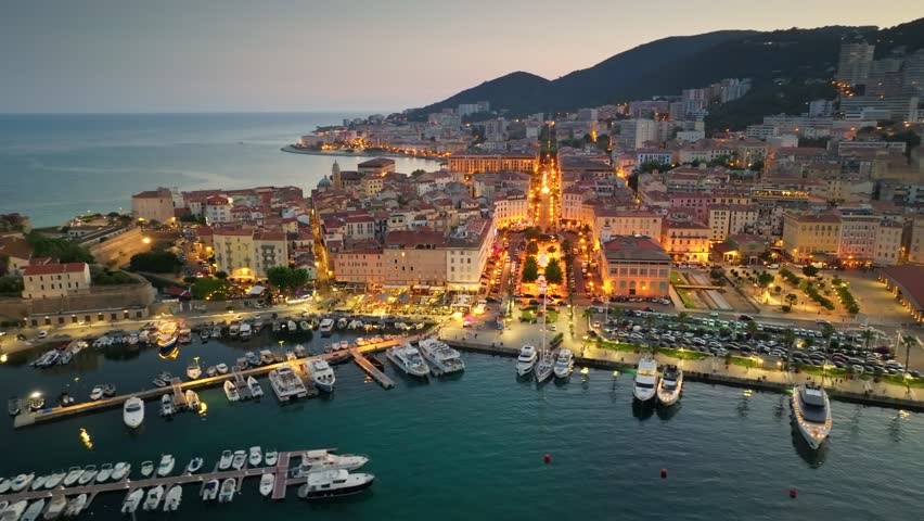 Corsica island, aerial evening shot of Ajaccio old town. Flying over harbor and old houses with city lights in Ajaccio - capital of Corsica, France