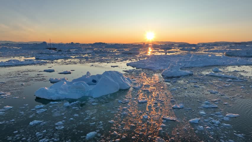 Sunset in Greenland nature. Aerial view of setting sun and pieces of melted icebergs. Glaciers melting, global warming, arctic nature landscape