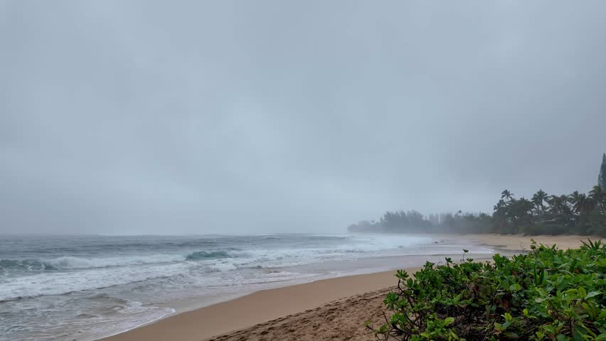 Sandy Haena Beach at Haena Beach Park on North Shore of Kauai, Hawaii on foggy day. Small, picturesque sand beach with occasional strong surf. It has a lifeguard station, restrooms, showers, campsites
