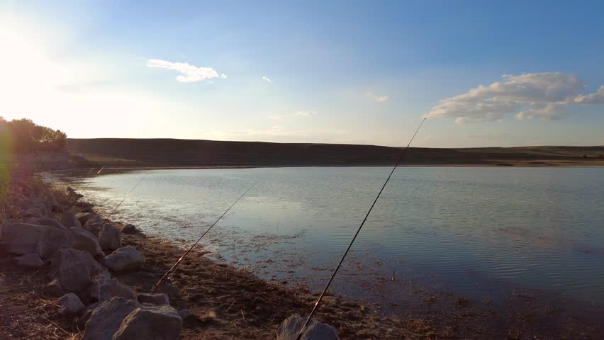 a fisherman fishing by the lake,a fisherman who casts his fishing rods into the lake and catches fish,