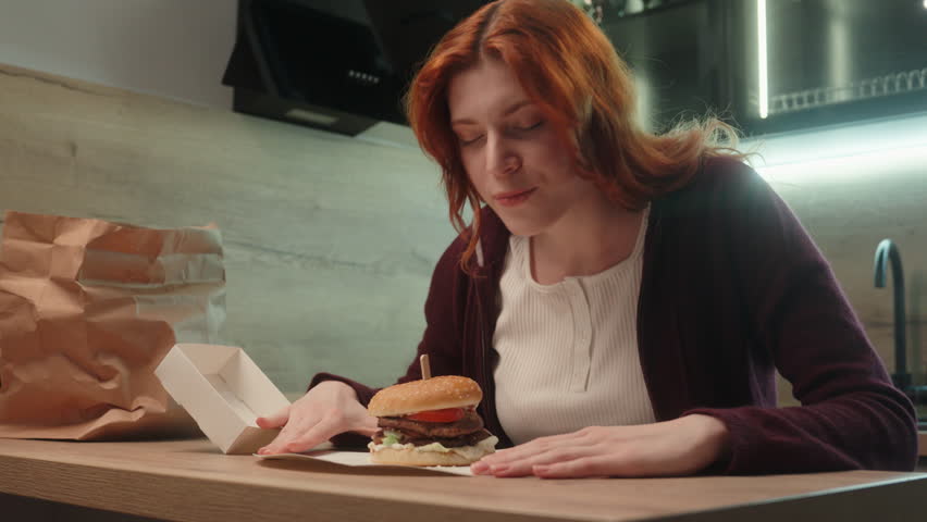 Amazed happy Caucasian 20s smiling hungry woman girl female customer shopper client open cardboard box fast food package sniffing burger hamburger scent enjoy tasty smell order delivery indoor kitchen