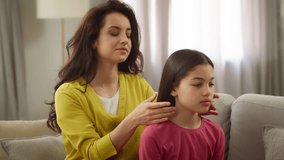Caring loving Caucasian mother female woman sister braiding hair making hairstyle coiffure smiling little girl child kid daughter sibling talk chatting happy family time together indoor home apartment - Powered by Shutterstock - Get 15% off with code: PIKWIZARD15