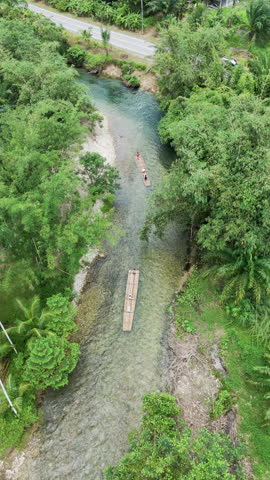 Drone shot aerial view  bamboo rafting tropical waterfall forest sunshine. Bamboo raft drifting jungle tree adventure holiday summer. Vertical aerial view shot.