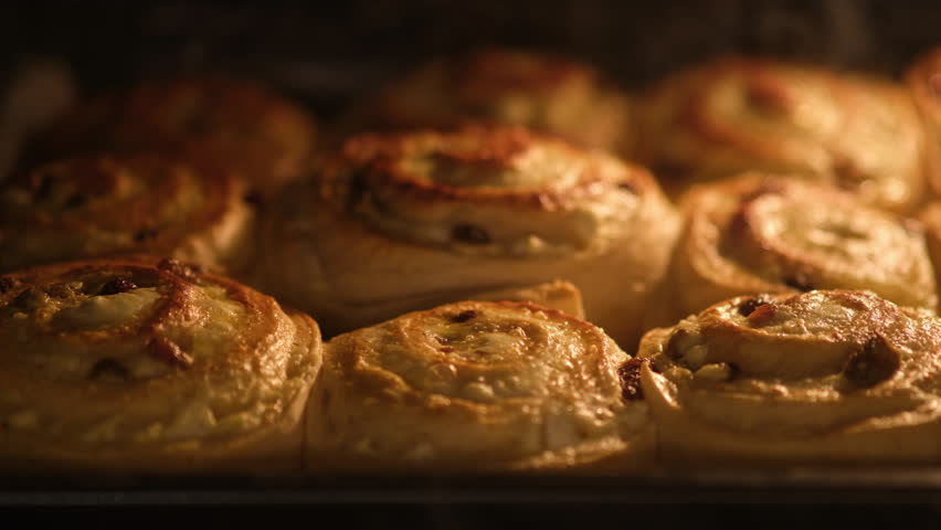 Rolls buns with raisins and cottage cheese baking in the oven, timelapse. Close-up food with warm lighting. Homemade dessert preparation concept