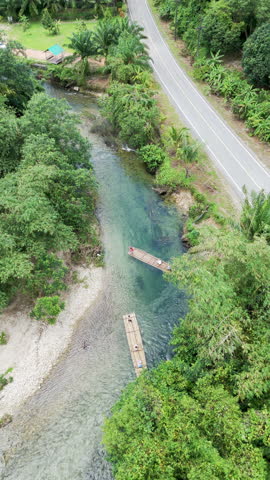 Rowing bamboo boat flowing through canal stretching. Travel natural adventures holiday summer. Vertical aerial view shot.