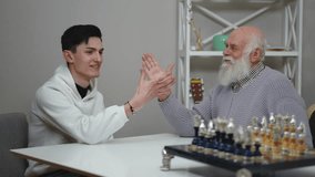 A young man and an elderly gentleman are joyfully sharing a memorable moment while enjoying a friendly chess game - Powered by Shutterstock - Get 15% off with code: PIKWIZARD15