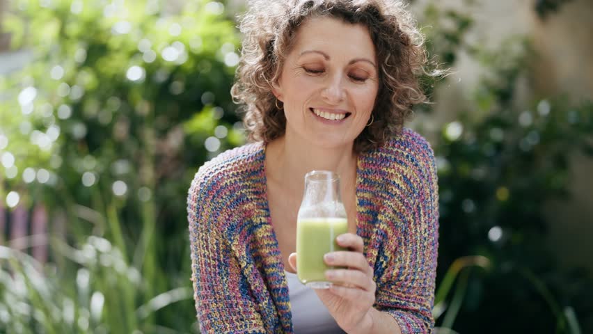 Video of  healthy mature woman drinking detox juice in the garden