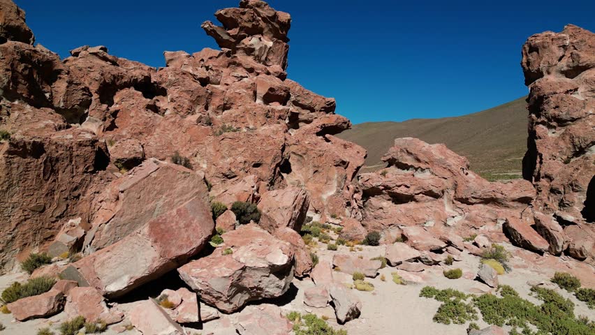 Drone flying up and revealing a large valley behind a volcanic rock formation in the Potosi distric of Bolivia. On the right the famous Camel Rock is recognizable in the distance
