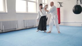 Two men training aikido with one applying joint arm control Sankyo technique They are dressed in traditional martial arts kimono and Hakama. Active people and Japanese culture 4K footage. - Powered by Shutterstock - Get 15% off with code: PIKWIZARD15