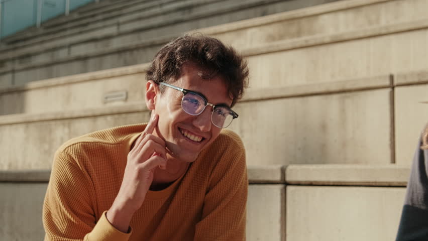 Multiracial group of young teenage students or hipster friends laughing together and having fun sitting on city street. Unity and community concept