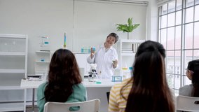 Elderly teacher teaches science course, holding laboratory flask in both hands, stand talk with students in class, summarize results experiment before class, make students understand experiment more. - Powered by Shutterstock - Get 15% off with code: PIKWIZARD15