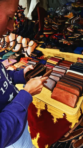 Shopping at Leather Goods Market Stall: Wallets and Sandals Display