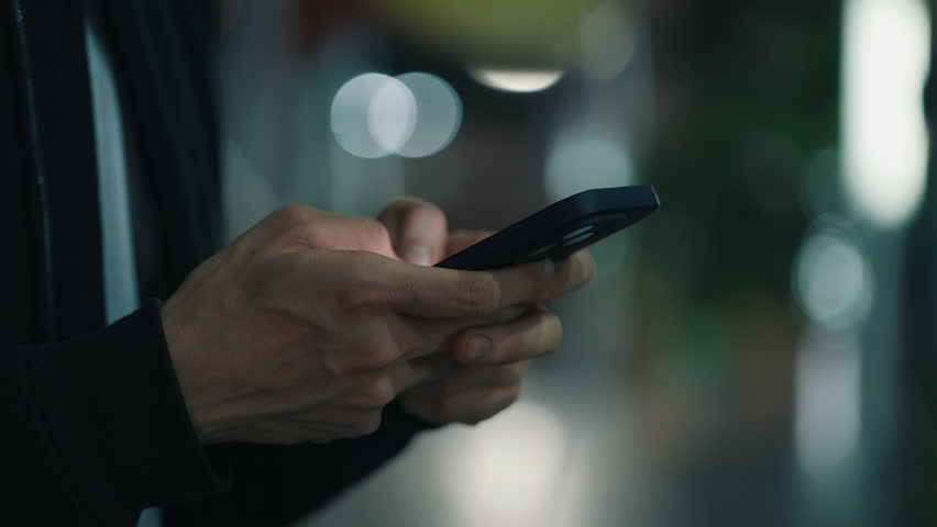 Close up hands of anonymous person using thumb fingers for entering text on cellular phone with sensor screen. Unrecognizable guy writing email while using tech device with wireless connection.