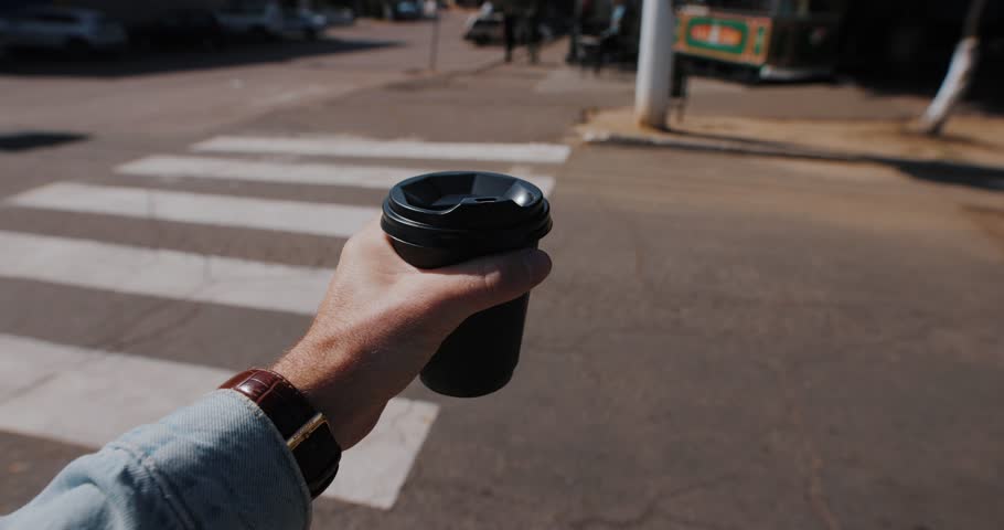 POV, male hand with takeaway coffee cup walking in a city