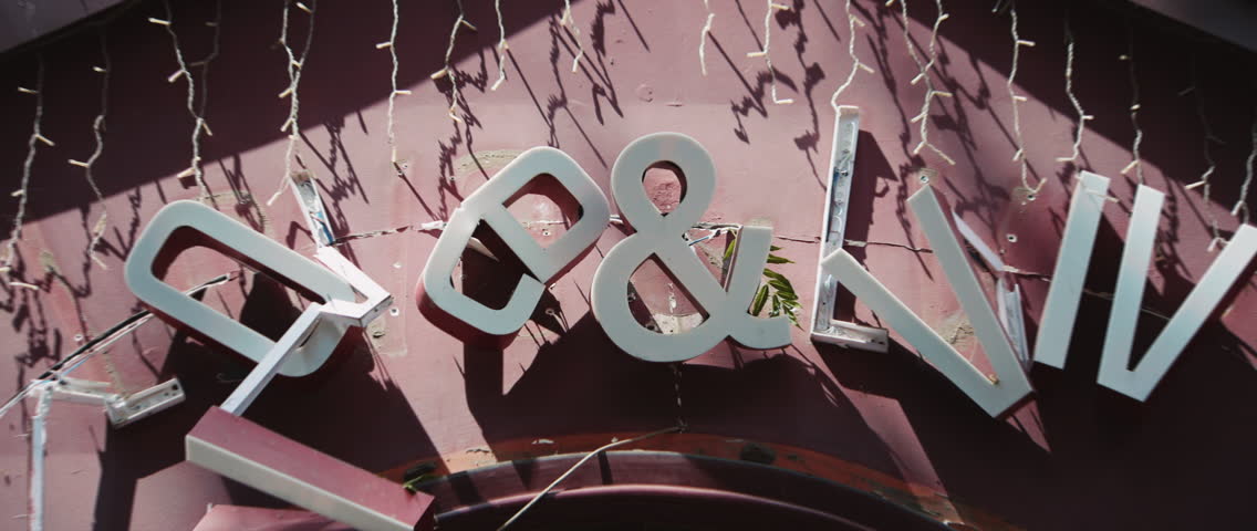 Close up shot of shop sign damaged after blast wave from missile strike on city. Daytime. Military aggression. War