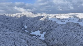 AERIAL: Spectacular drone shot of the snowy forest covered mountains and valleys in a rural part of Slovenia, Europe. Winter sunshine illuminates the hilly forested landscape covered in fresh snow. - Powered by Shutterstock - Get 15% off with code: PIKWIZARD15
