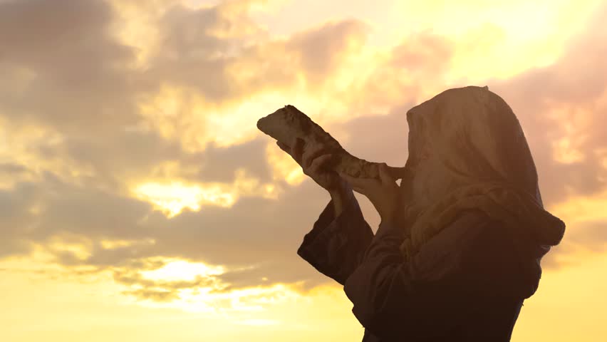 the silhouett of  Jewish man blowing the Shofar horn of Rosh Hashanah New Year