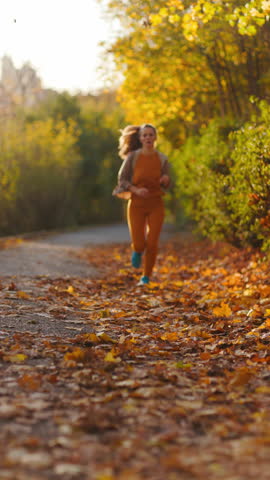 Hello autumn. elegant 40 years old woman in fitness clothes in the park running.
