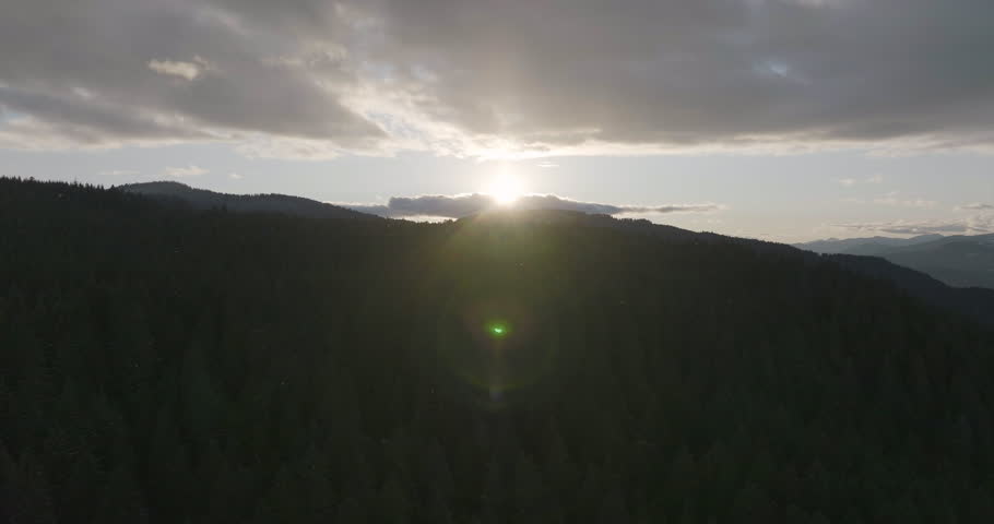 Light snow falling on Gifford Pinchot National Forest in Washington State at sunset, aerial view.