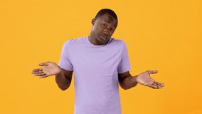 A young man wearing a purple t-shirt stands against a vibrant yellow backdrop, shrugging his shoulders in a casual gesture of uncertainty or indifference. - Powered by Shutterstock - Get 15% off with code: PIKWIZARD15
