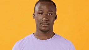 A young man with an expression of surprise stands with a neutral posture. He is wearing a light purple shirt and is set against a vibrant orange backdrop, capturing a moment of unexpected emotion. - Powered by Shutterstock - Get 15% off with code: PIKWIZARD15