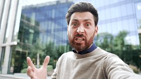 Webcam view Angry dissatisfied businessman arguing talking on video call on phone looking at camera standing on street near business office building. Excited executive emotionally talks about problems - Powered by Shutterstock - Get 15% off with code: PIKWIZARD15