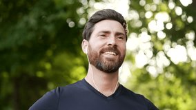 Happy joyful athlete relaxing with closed eyes standing in urban city park. Smiling handsome bearded runner breathes deeply and enjoys being in nature while resting after a morning workout. Close up - Powered by Shutterstock - Get 15% off with code: PIKWIZARD15