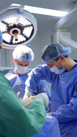 Male surgical team working in the surgery room. Doctor uses metal tool and puts it on the surgical stand. Vertical video.