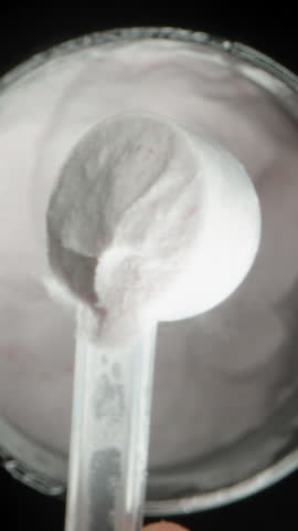 Vertical video. A Man Scoops White Powder Into A Measuring Spoon, Brings It To The Camera, And Pours It Back Into The Container. Concept Of Rejecting Harmful Supplements.