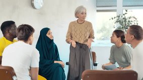 Friendly and calm senior female psychotherapist or facilitator leading group therapy session with women and men of different ages and nationalities sitting on chairs in circle. High quality 4k footage - Powered by Shutterstock - Get 15% off with code: PIKWIZARD15