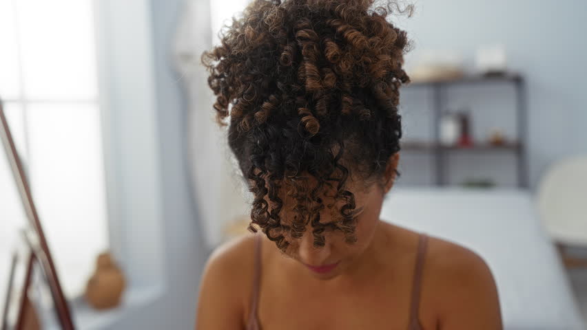Woman with curly hair in a wellness center, spa, or salon, relaxing in an indoor room while showcasing beauty and wellness with a serene ambiance.