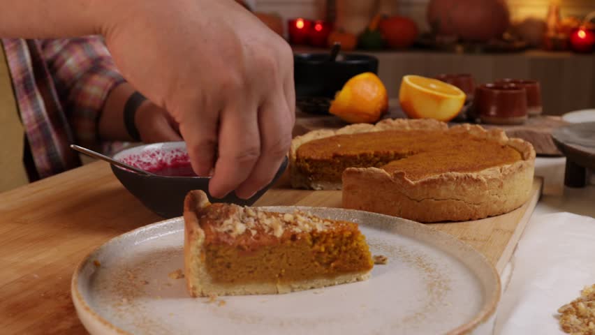 a man decorates a pumpkin pie with whipped cream and pecans