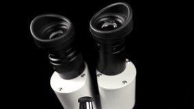 White Compound Microscope Rotating Over Black Background Closeup