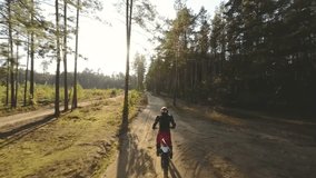 Aerial FPV footage of professional motorcyclist wearing equipment riding light enduro bike trough the sunny summer forest. Motocross sport, off-road motorcycle race adventure. - Powered by Shutterstock - Get 15% off with code: PIKWIZARD15