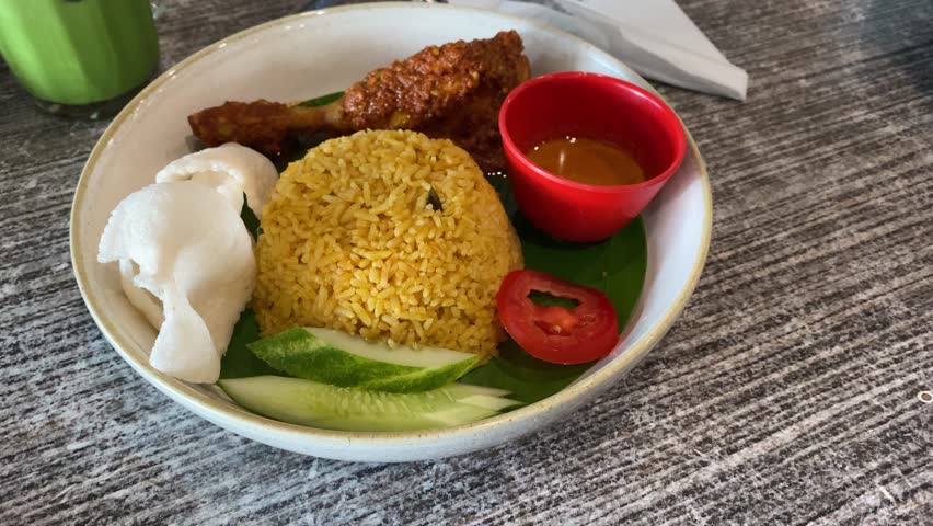 Indonesian fried rice served with chicken rendang. Fried rice asian popular food served with cucumber slices and crackers.