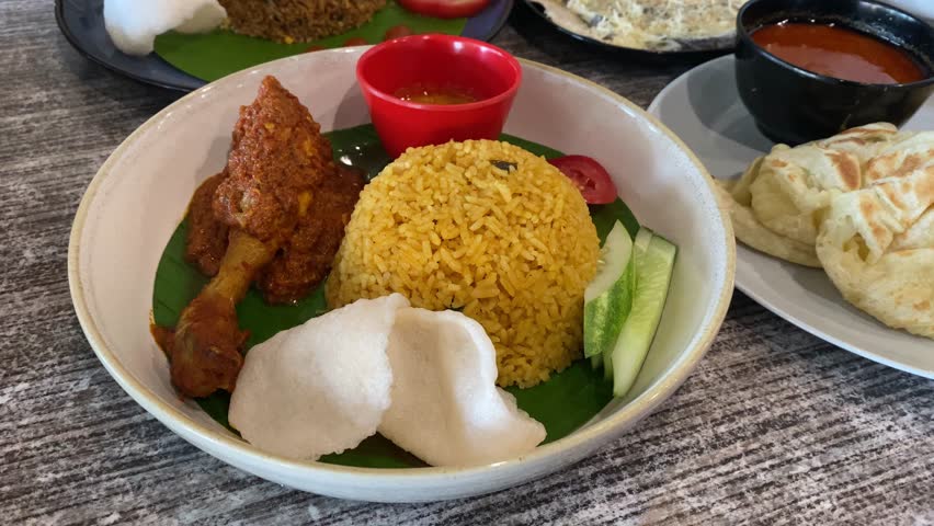 Indonesian fried rice served with chicken rendang. Fried rice asian popular food served with cucumber slices and crackers.
