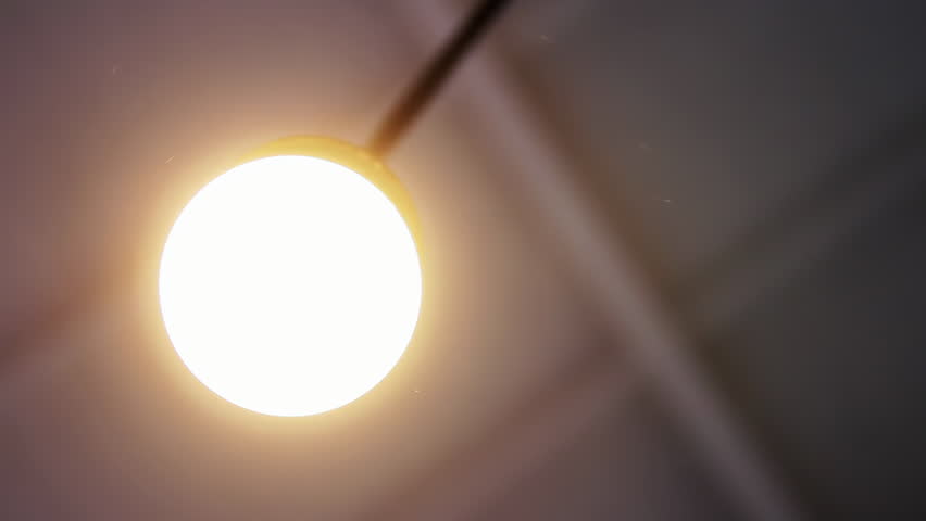 Zooming In on a Round Ceiling Lamp as It Lights Up in a Room - 4K