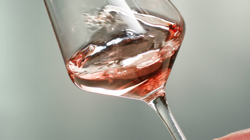 Rose Orange or white wine bottle and glass against a sunset in a peaceful vineyard, pouring of ecological natural wine. Cheers, hands with wine glasses, drinking alcohol.