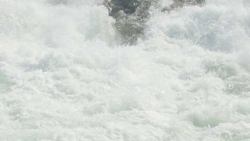 Spawning salmon fish jumps out of frothing whitewater below waterfall