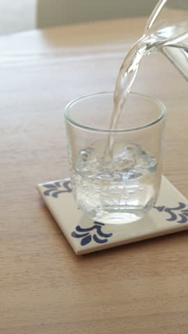 Drinking water filling glass on table in modern kitchen aesthetic