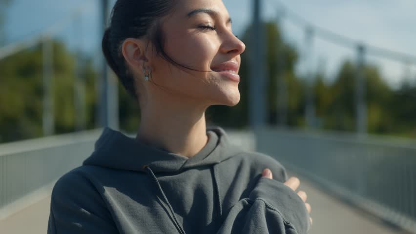 Headshot of a smiling 18-year-old brunette teenage girl outside in the park. Her youthful energy and carefree attitude are captured in this close-up portrait.