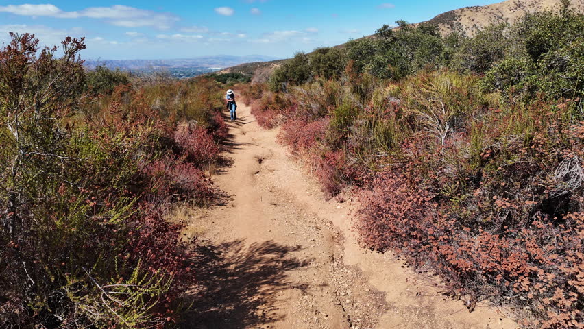 Hiking a Trail in a Chaparral Hilly Habitat looking at a Woman Exploring the area while hiking