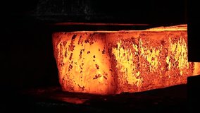 Close-up of a large red-hot piece of metal being heated in a forge. Red-hot metal billet on a roller table of a rolling mill. - Powered by Shutterstock - Get 15% off with code: PIKWIZARD15