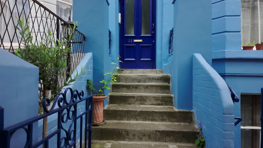 Beautiful vintage dark blue door leading into light blue painted house. Entrance to the living space from the street with a nice door and steps.