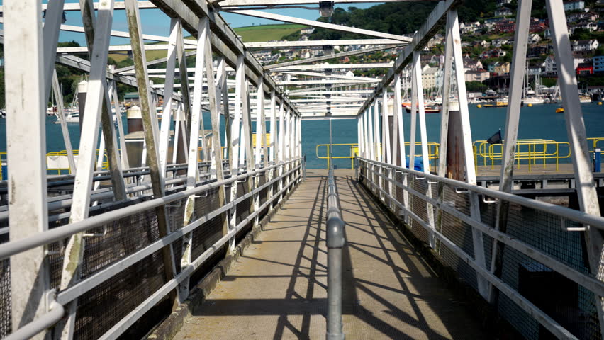 White metal pedestrian bridge leading to boarding of tourist boats. Passage leading to public water transport on a sunny day.