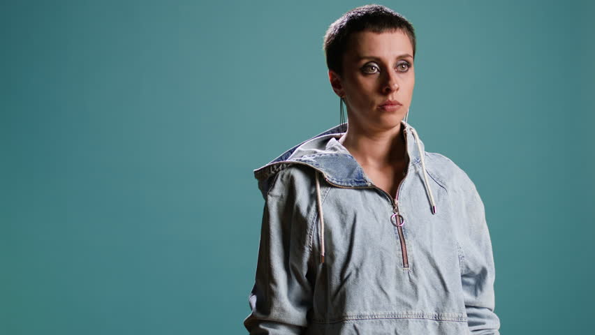 Scared nervous woman covering her mouth in shock against blue background, looking at something scary. Person with a street style being anxious and frightened, concerned afraid girl. Camera A.